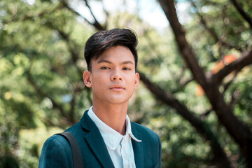 A handsome and young Filipino college student in smart casual wear. Serious look. At the park or...