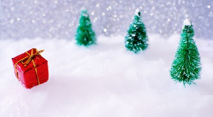 Christmas home decoration with Little handmade gift box in a snow covered miniature evergreen forest and bokeh light for copy space.
