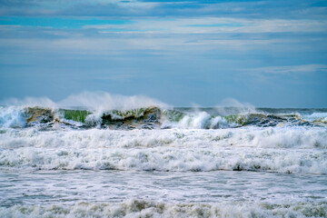 Dramatic storm waves curling and disturbing the beach at Mount Maunganui