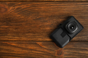 Modern car dashboard camera on wooden background, top view. Space for text