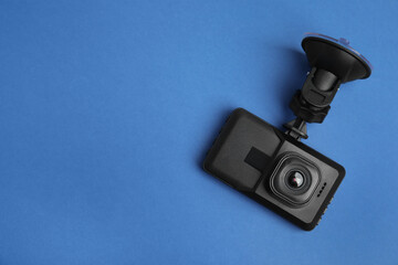 Modern car dashboard camera with suction mount on blue background, top view. Space for text - obrazy, fototapety, plakaty