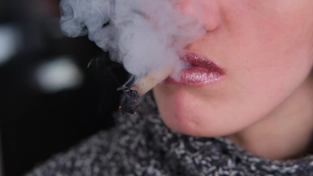 Female lips smoking  cigarette. Close-up portrait, red light
