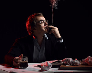 Adult man in glasses, shirt and jacket sits behind desk, writing table with book sheets and...