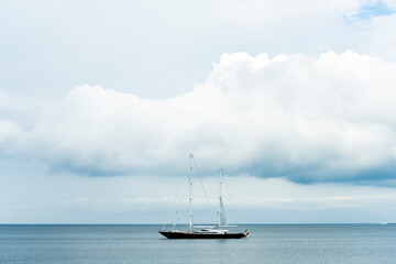 Fototapeta premium Stunning view of a luxury sailboat sailing on a beautiful calm sea during a dramatic, cloudy day.Sardinia, Italy. Recreational pursuit, copy space.