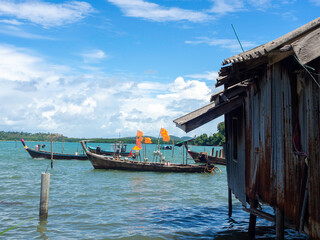 Fototapeta na wymiar Beautiful seascape summer background. Fisherman house with many local longtail boat on the sea and sky background on a sunny day in Thailand.