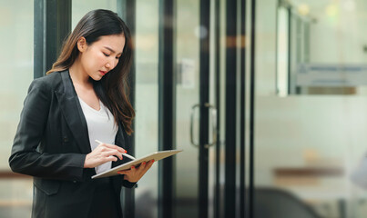 Beautiful businesswoman using stylus pen writing on tablet screen while standing in office room...
