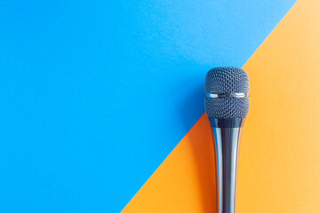 Microphone on a colorful blue and orange geometric background close up. Singing, writing music, karaoke online, creativity, vocals concept, symbol. Singing lessons - obrazy, fototapety, plakaty