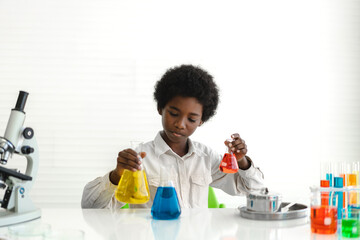 African american cute little boy student child learning research and doing a chemical experiment while making analyzing and mixing liquid in glass at science class on the table.Education