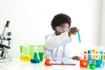 African american cute little boy student child learning research and doing a chemical experiment while making analyzing and mixing liquid in glass at science class on the table.Education