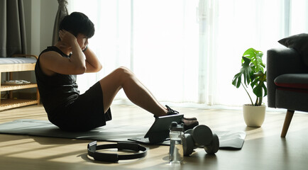 Young male in sportswear workout in living room.