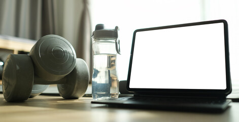 Mock up computer tablet, dumbbells, water bottles on floor in living room. Workout training at home.