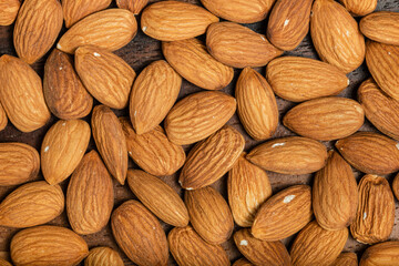 Fototapeta premium Background of big raw peeled almonds situated arbitrarily. Top view. Macro photography.