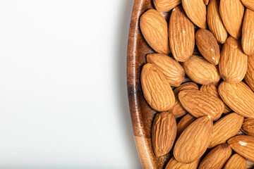 Background of big raw peeled almonds in a wooden bowl. Tip view.