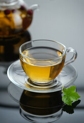 Yellow herbal tea in glass cup with leaf. Close-up  cup of freshly brewed hot tea.