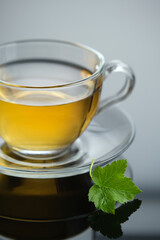 Yellow herbal tea in glass cup with leaf. Close-up  cup of freshly brewed hot tea.