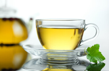 Yellow herbal tea in glass cup with leaf. Close-up  cup of freshly brewed hot tea.