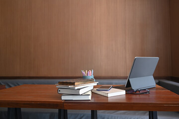 Mock up computer tablet, books, pencil holder, smart phone and glasses on wooden table.