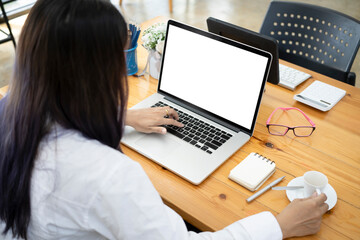 Back view of woman office worker working with computer laptop at her office desk.