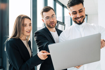 Three business people using laptop in office