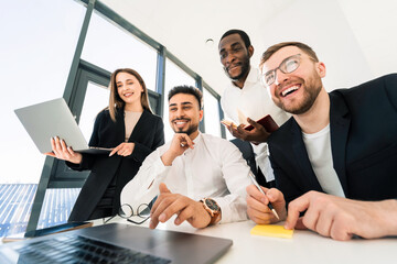 Young multiracial ambitious team of programmers are thinking about a new project while sitting behind laptop
