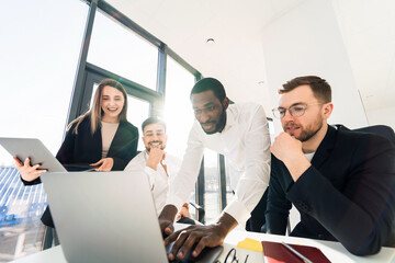 People of different ethnic groups working together in the office on a laptop