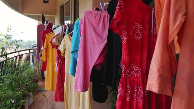 Hanging clothes on washing line for drying in balcony of apartment building a summer day Kerala India Sri Lanka 4K slow motion video. wash stain dirty clothing use detergent , drying dress in sun.