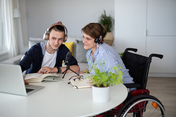 Disabled people sitting at the table indoors at home, recording podcast at home.