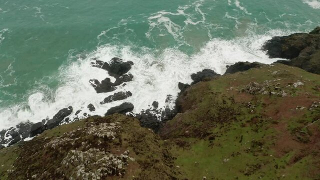 Aerial tilt up from the crashing waves at land's ends to the open Atlantic Ocean. 
