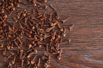 Dry cloves spice on a wooden background. Heap of Indian clove buds and flowers, natural organic product. Healthy, spicy ingredient for cooking