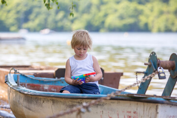 Little toddler child, blond boy, playing with pop it antistress toy in the park in a boat