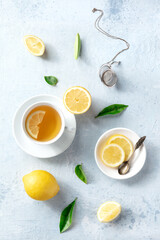 Lemon tea in a cup, overhead flat lay shot on a slate background. Organic lemons, green leaves and the natural medicine of the healthy beverage