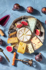 Cheese tasting with red wine and fruit, shot from the top. A delicious cheese platter with Brie,...