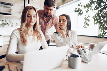 Two female and one male business partners looking at computer screen and discussing their project