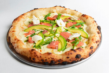 Delicious pizza with salmon, cheese, avocado and fresh arugula. Over white background.