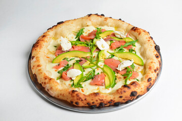 Delicious pizza with salmon, cheese, avocado and fresh arugula. Over white background.