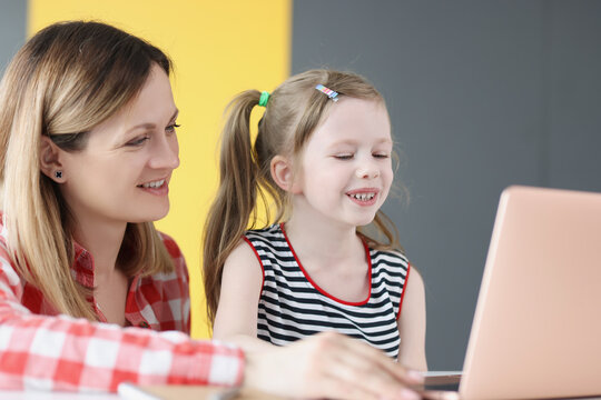 Young smiling woman conducts classes with child on laptop