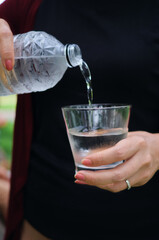 A woman pouring water into a drinking glass