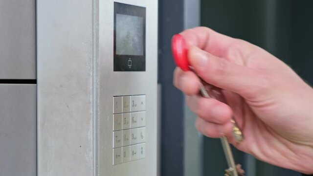 Male using intercom at residential building entrance. opens electronic code lock. man hand entering security system code, pressing button with index finger intercom device entrence door.