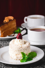 Coconut cake on a white plate with other food on the background.