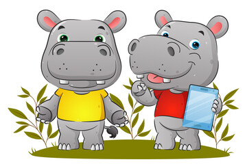 The couple of the hippopotamus is holding the tablet and explaining something in the garden