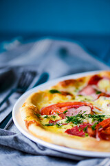 Cooked pizza on aged blue wooden surface background with copy space, side view.
