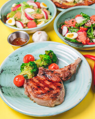 Salad with spinach, eggs and radish in a bowl over bright yellow background. Fish fillet steak, potato and cheese pizza.