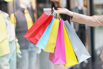 Multicolored paper bags on female hands on background of shopping mall