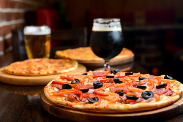 Fresh craft beer and pizza with vegetables and meat. Party concept, different kinds of pizza with...