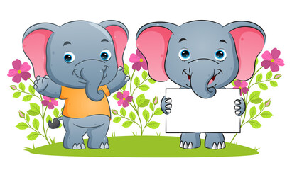 The happy elephant is holding a blank banner and giving the support in the garden