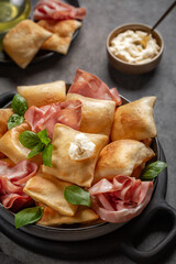 Close-up of Italian crescentine or gnocco fritto with mortadella and soft cheese. Traditional appetizer.