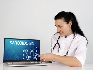  SARCOIDOSIS inscription on the screen. Close up Doctor hands holding black laptop.