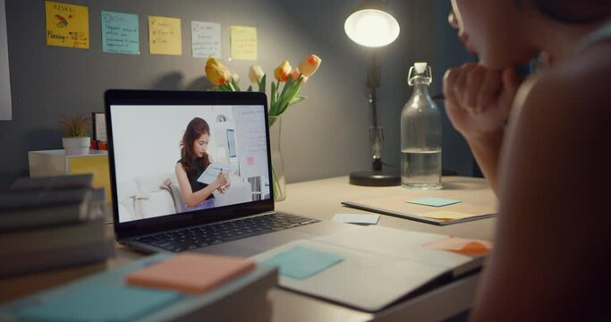 Close up of Young Asia teen girl student distance learning lesson with online teacher and study on laptop screen in living room at home night. Remotely, Social distancing, quarantine for corona virus.