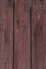 Wooden planks, painted with burgundy paint. The close-up conveys the texture of the slightly cracked paint over the wood grain well. The photo is perfect as a photo background