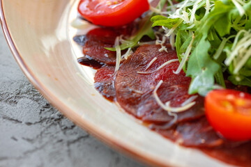 Beef carpaccio with arugula and parmesan on gray surface